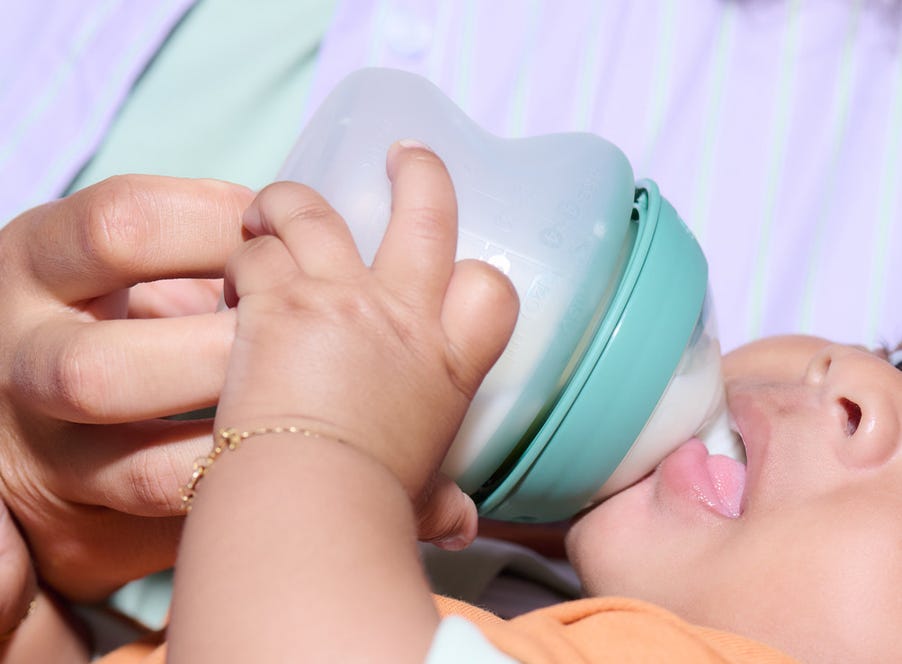 a mum bottle feeding her baby using a tommee tippee bottle