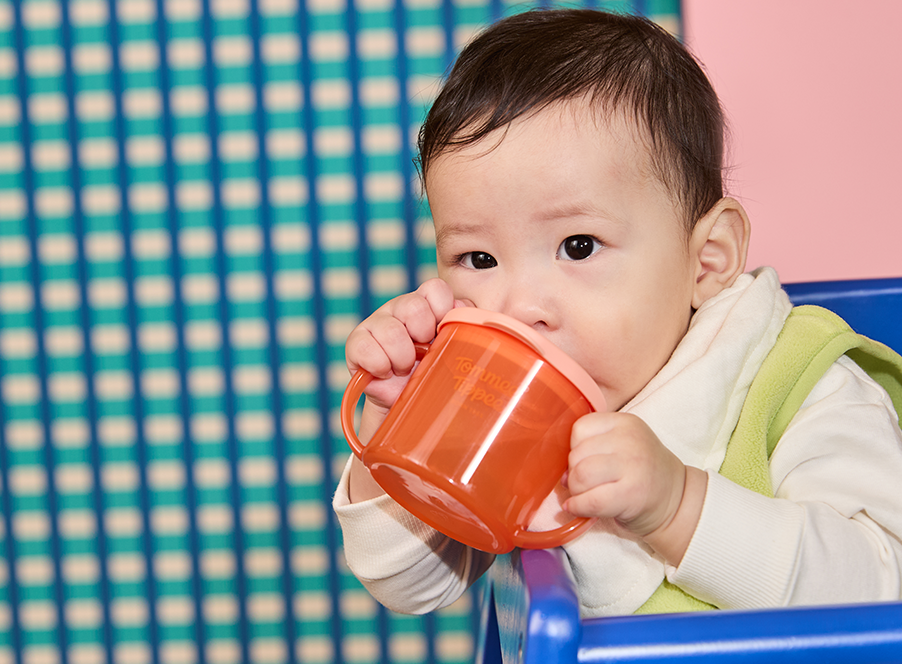 baby drinking from orange cup