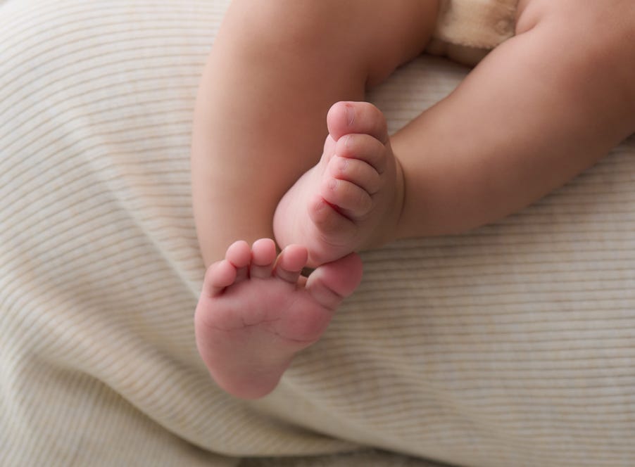 Close-up of a newborn baby's feet resting on mum's lap.