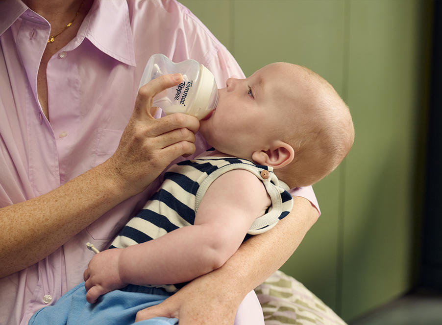woman bottle feeding baby in striped top