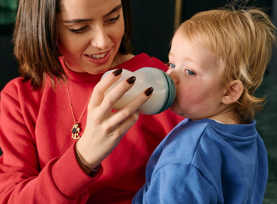 a baby feeding from a tommee tippee bottle