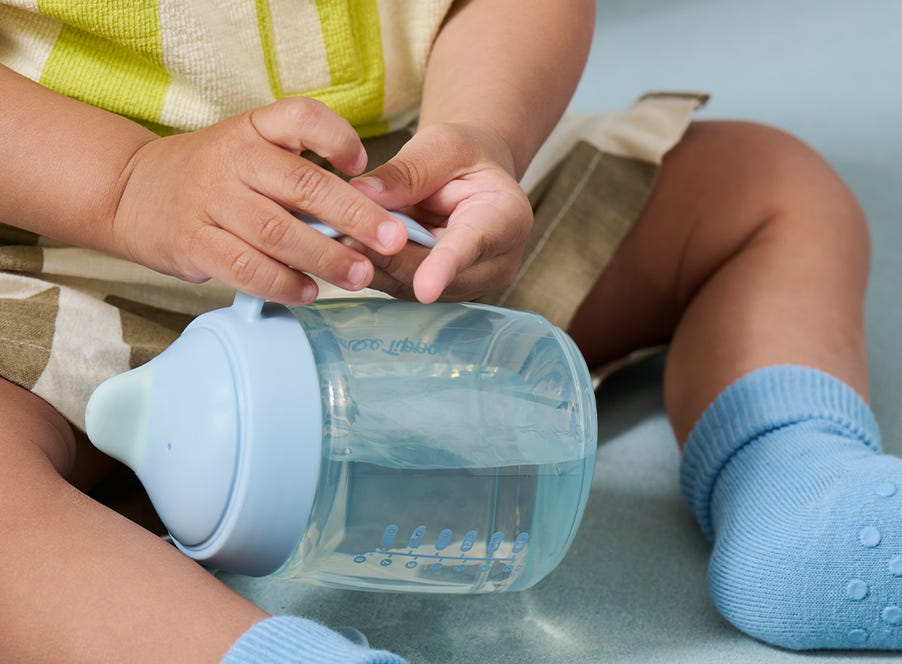 a baby drinking from a blue cup