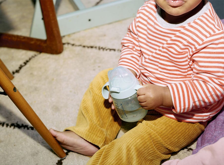 a toddler drinking from a blue cup