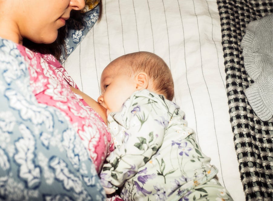 a mum sitting in bed breastfeeding her newborn baby