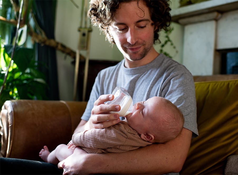 a dad feeding his baby expressed breast milk