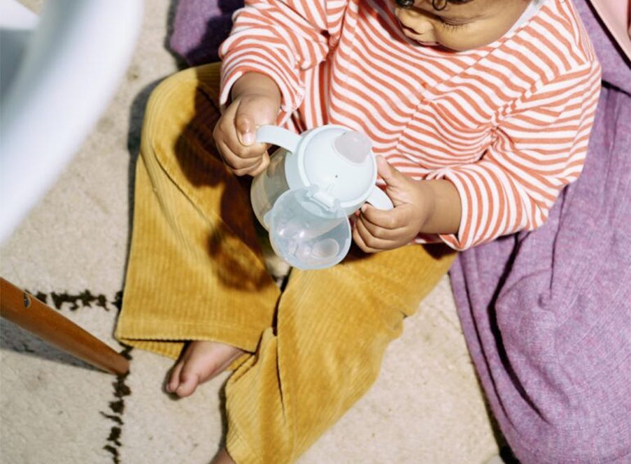 a toddler drinking from a tommee tippee cup
