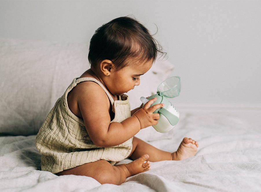 a baby drinking from a tommee tippee cup