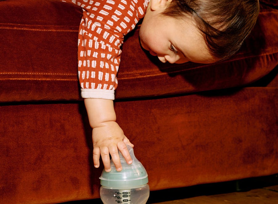 a baby reaching for a tommee tippee bottle