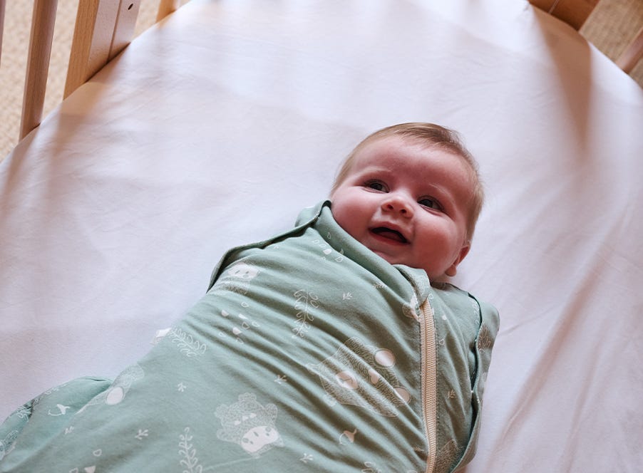 a baby in their cot wearing a Tommee Tippee sleepbag