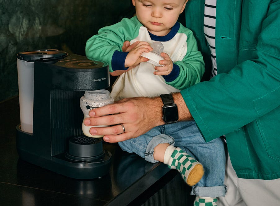 a dad making a bottle using a tommee tippee perfect prep machine