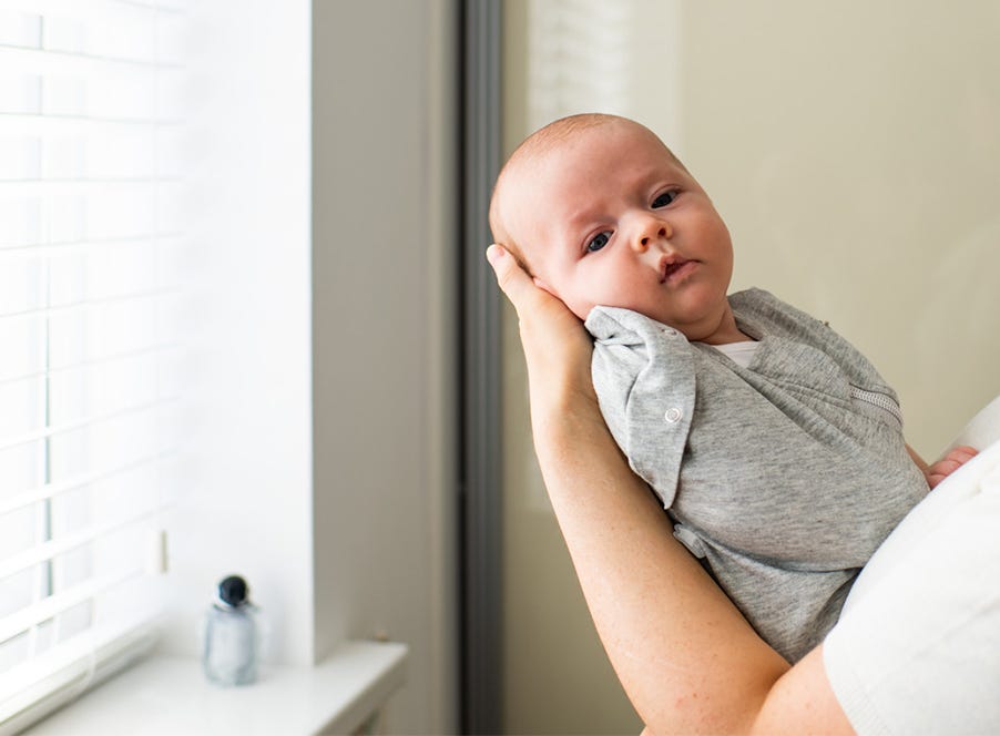mum dressing her baby for bed in a tommee tippee swaddle bag