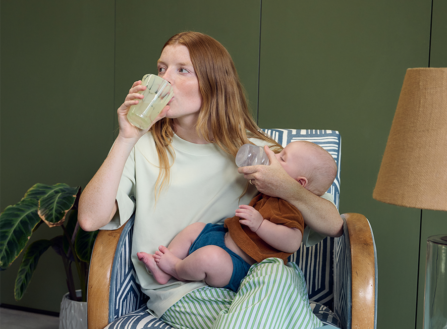 mum feeding baby and drinking from glass
