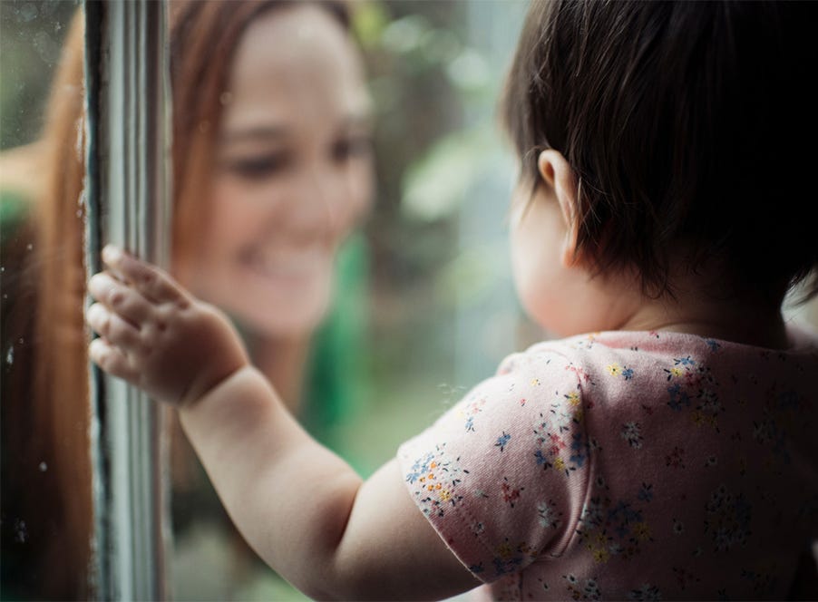 a mum looking through the window at her toddler