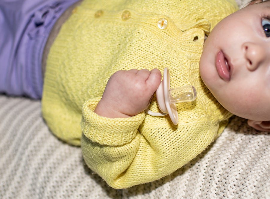 baby wearing a yellow cardigan