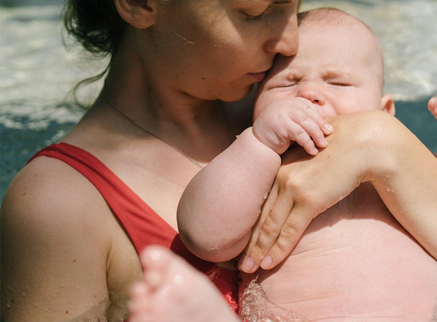 a baby in a pool with their mum