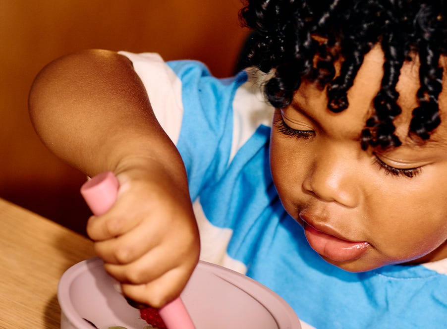 a toddler eating using a tommee tippee bowl and spoon