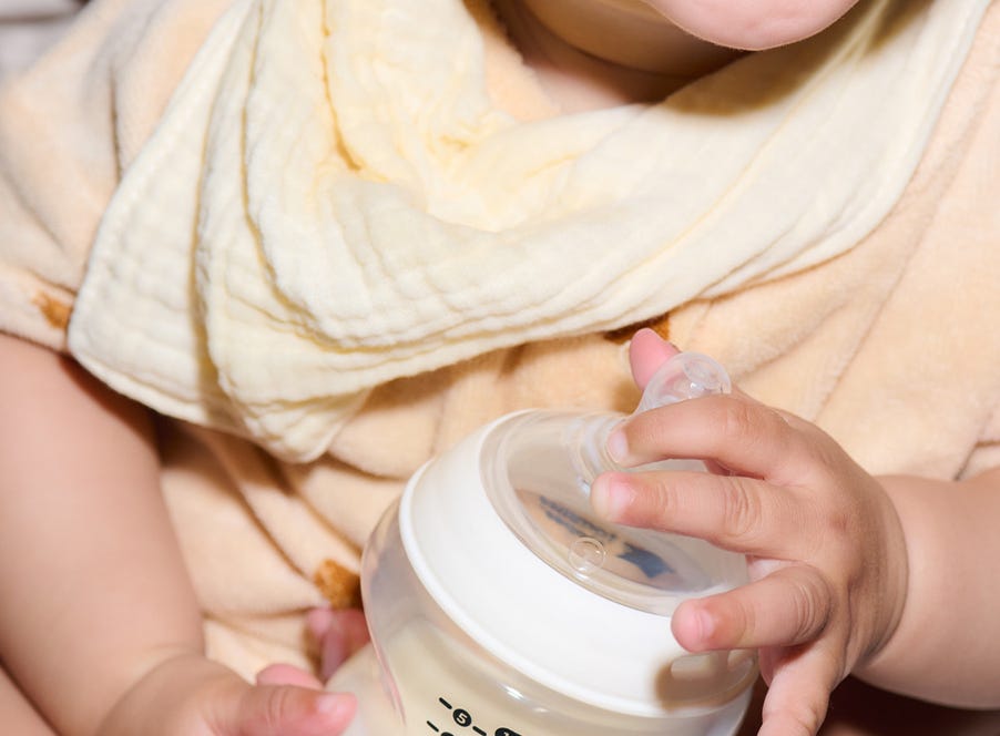 a baby holding a tommee tippee bottle