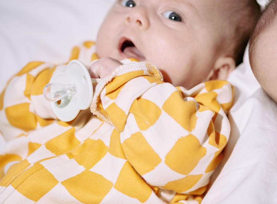a baby holding a soother