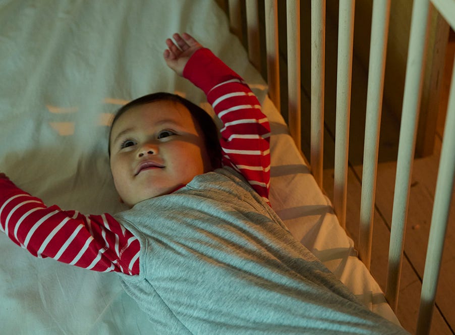 a baby stretching in their cot