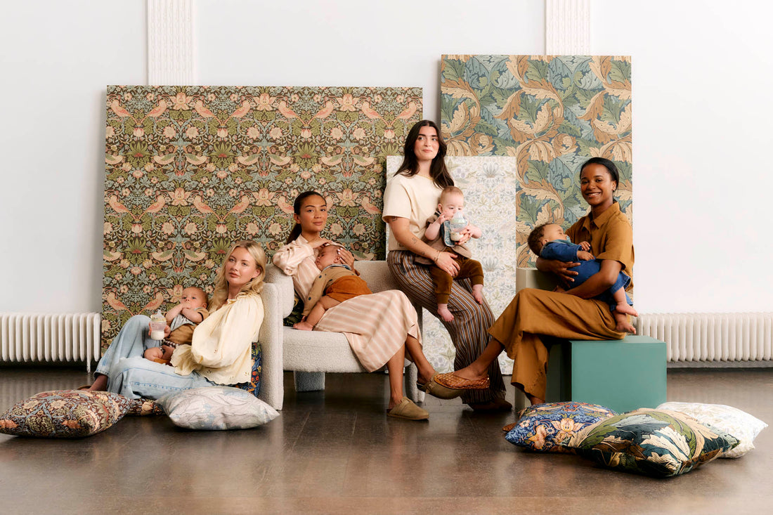 Four mums sitting on chairs and floor with babies in big room with patterned backdrops behind them
