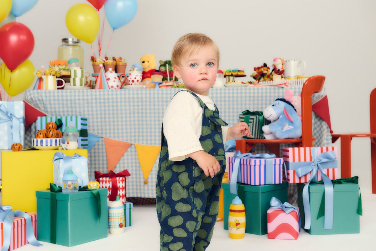 baby standing in front of birthday party table