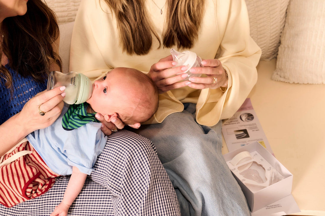two mothers sitting down feeding baby
