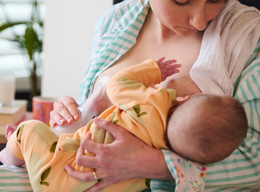 a mum breastfeeding her baby while using a tommee tippee breast pump