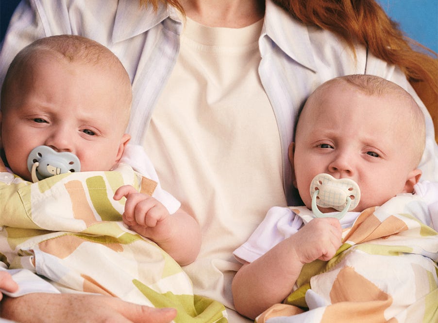two babies with tommee tippee pacifiers in their mouths