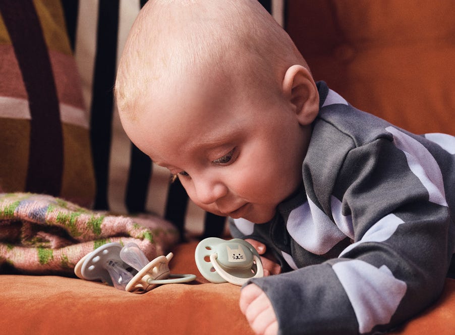a baby holding a tommee tippee soother