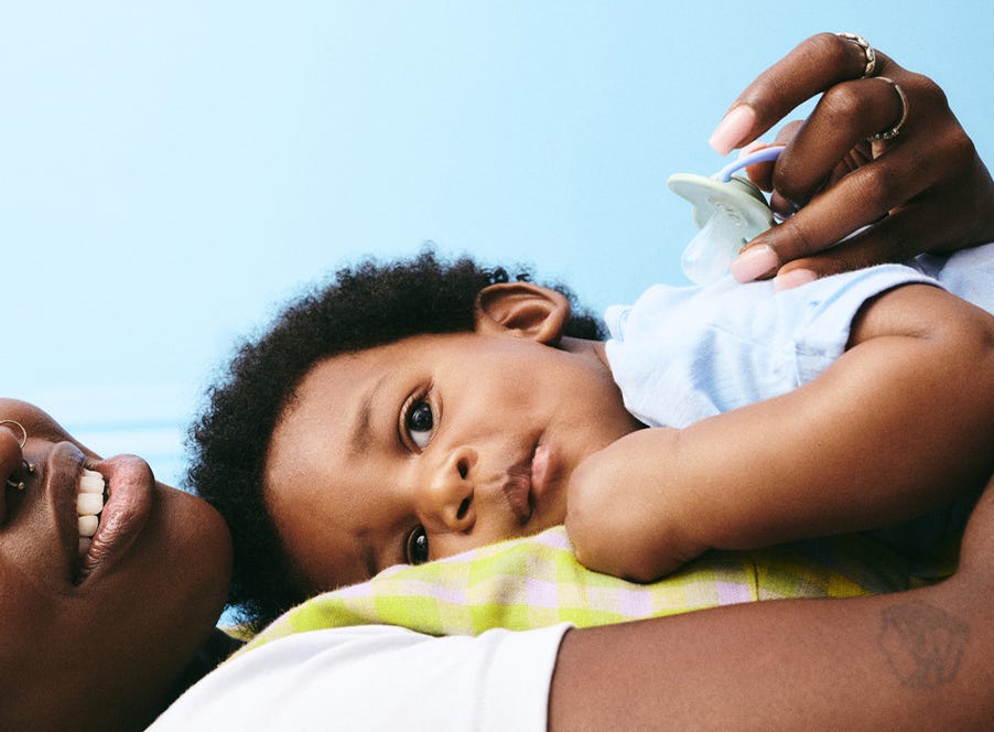 a mum holding her baby and a tommee tippee soother