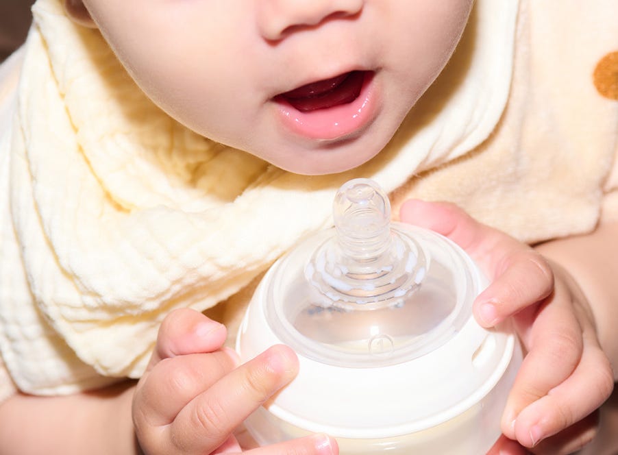 a baby holding a tommee tippee bottle
