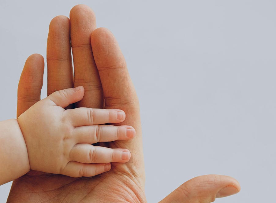 a newborn baby's hand on top of their dads hand