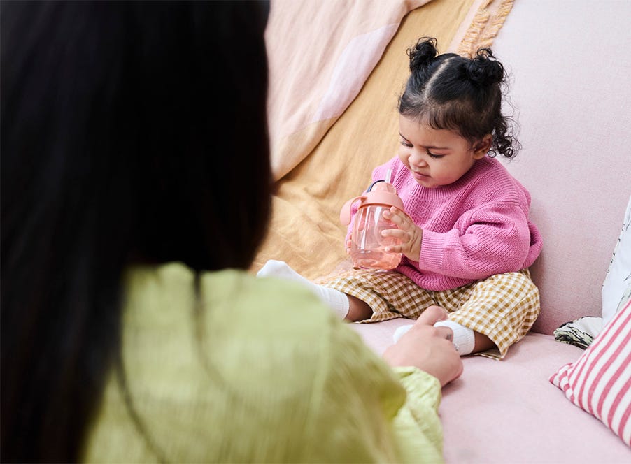 a toddler wearing a pink jumper