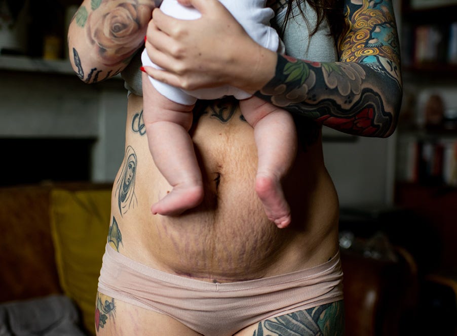 a postpartum mum with tattoos holding her baby
