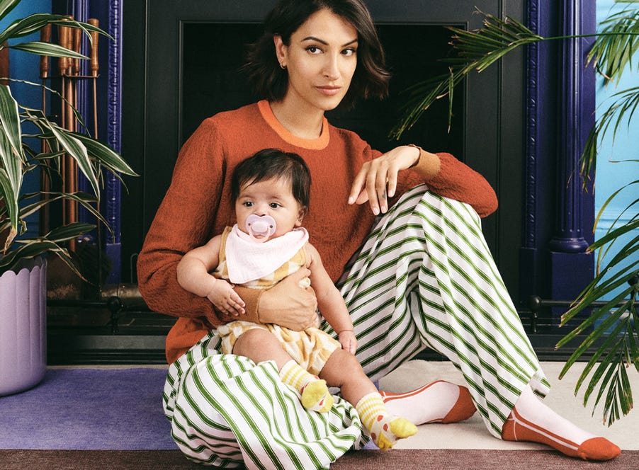 a mum wearing striped trousers sitting on the floor with her baby