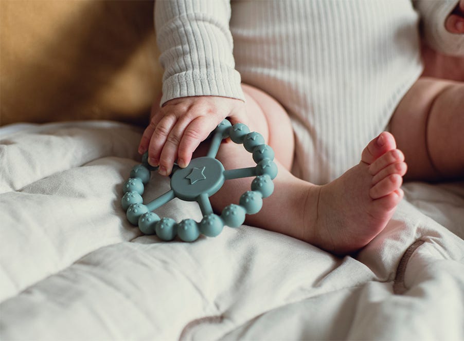a baby holding a blue teething ring