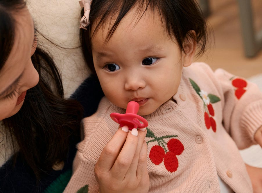 a toddler wearing a cherry-pattern cardigan
