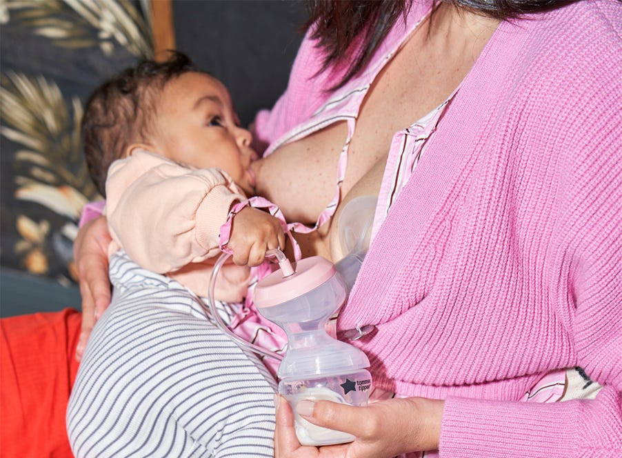 a mum wearing a pink cardigan breastfeeding her baby