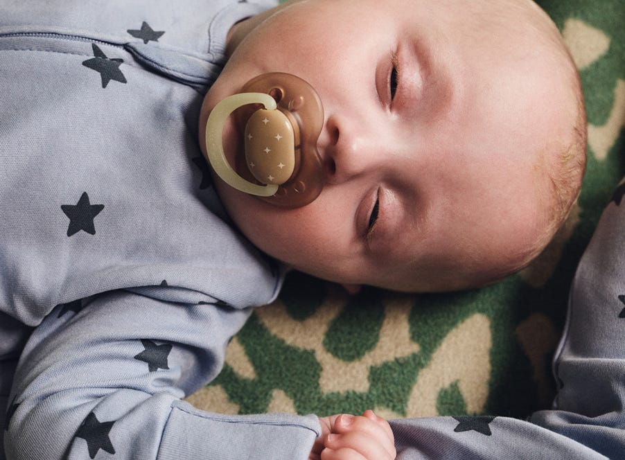 a baby sleeping with tommee tippee dummy