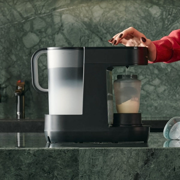 Gros plan sur une femme utilisant une machine Perfect Prep pour préparer un biberon