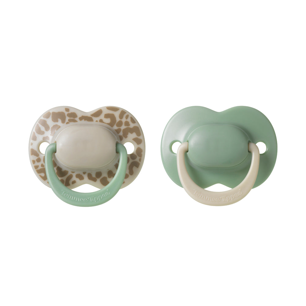 Two baby pacifiers, one with a leopard print and the other plain, on a white background.