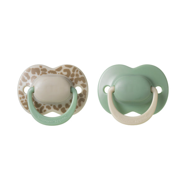 Two baby pacifiers, one with a leopard print and the other plain, on a white background.