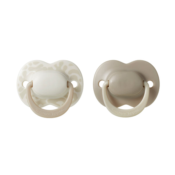 Two beige pacifiers on a white background