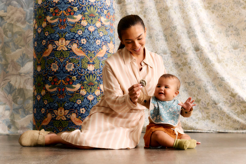 mum and baby sitting on floor, baby reaching for soother