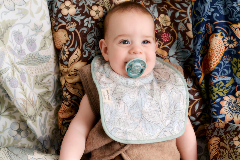 baby with soother in mouth smiling