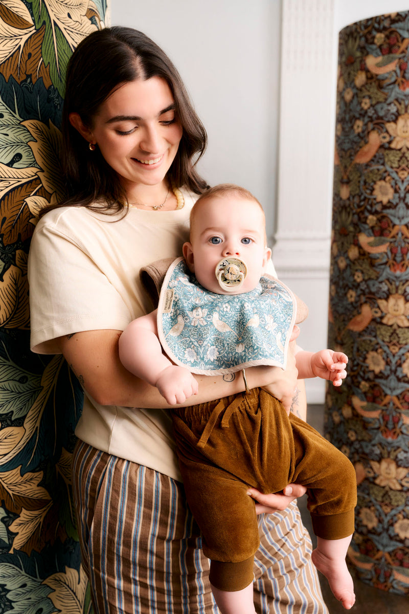 mum holding baby with soother in mouth and wearing bib