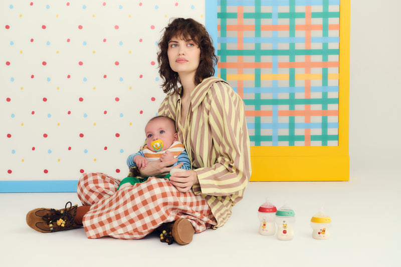 woman sitting with baby next to bottles 