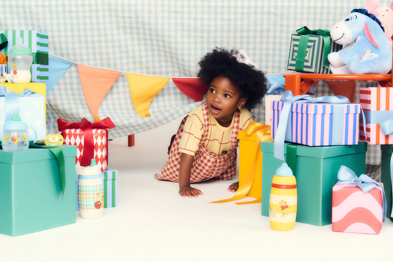 girl crawling under table surrounded by presents