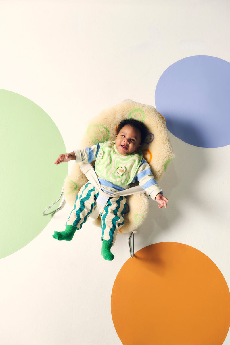 baby lying in bouncer with spots on floor