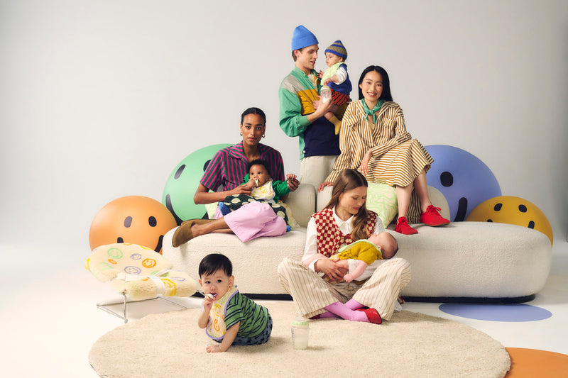 parents sat together on a couch with their babies with smiley faced balls around